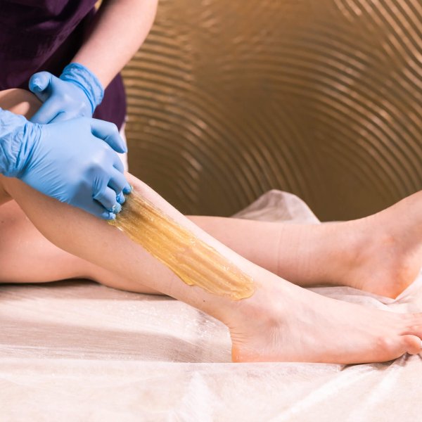 Sugaring epilation skin care with liquid sugar at legs. You can see her smooth and hair free legs after hair removal close-up. Beauty and cosmetology.